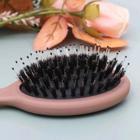 Brosse Poil de Sanglier en gros plan sur les poils posée sur un plan vert avec tulipe décorative à côté