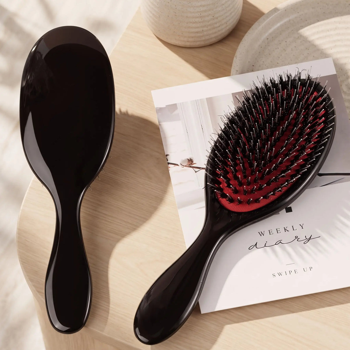 brosse poil de sanglier naturel noire posée sur un plan crème 