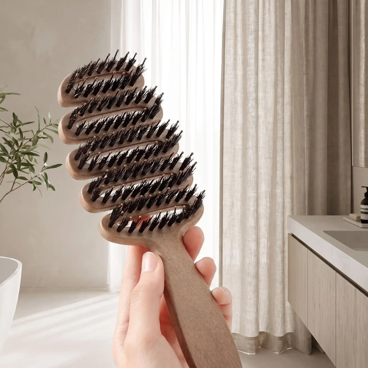 brosse poil de sanglier naturel une main qui tient la brosse afin d'en montrer les caractéristiques