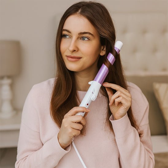 Jeune femme mi vingtaine qui se coiffe les cheveux avec le fer bouclant de couleur violet 