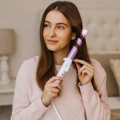 Jeune femme mi vingtaine qui se coiffe les cheveux avec le fer bouclant de couleur violet 