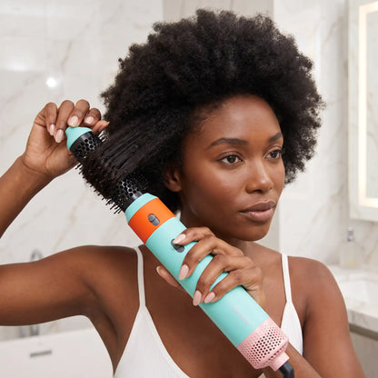 jeune femme aux cheveux bouclés qui se coiffe avec la brosse chauffante 5 en 1