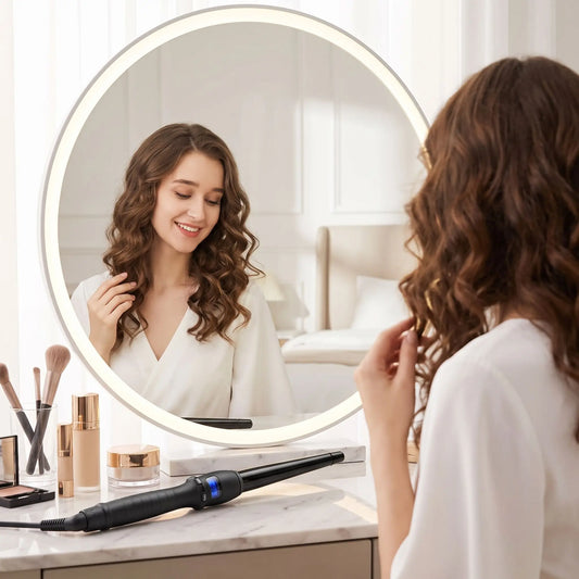 jeune femme aux longs cheveux bruns qui admire ses boucles dans le miroir et posé devant elle, le boucleur conique noir 