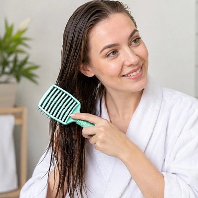 Jeune femme aux longs cheveux humides bruns qui brosse ses cheveux avec la brosse à cheveux verte