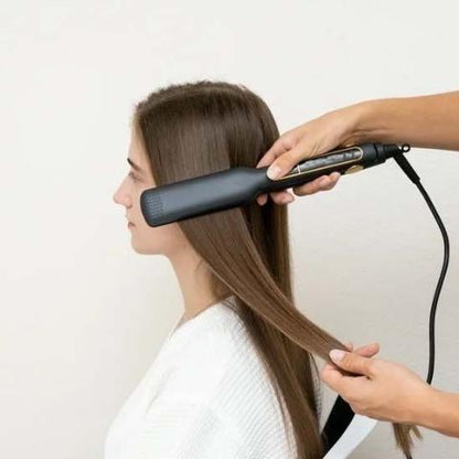 Jeune femme d'environ 20-25 ans longs cheveux bruns qui se fait coiffer avec le lisseur par une professionnelle de la coiffure