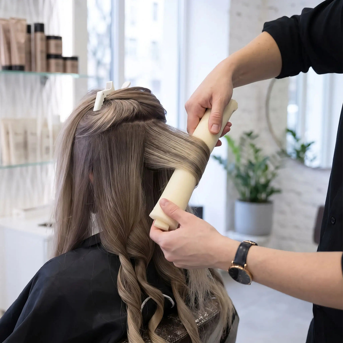 professionnelle de la coiffure installant des boucleurs sans chaleur dans les cheveux longs de sa cliente