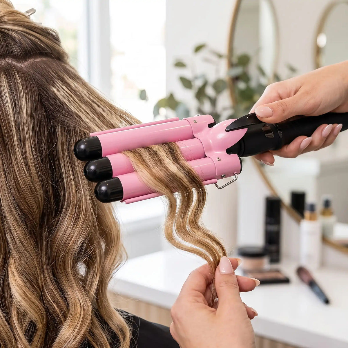 professionnelle de la coiffure qui boucle les cheveux de sa cliente avec le boucleur 3 tubes rose