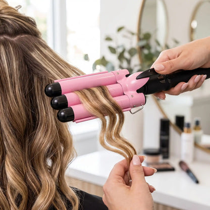 professionnelle de la coiffure qui boucle les cheveux de sa cliente avec le boucleur 3 tubes rose
