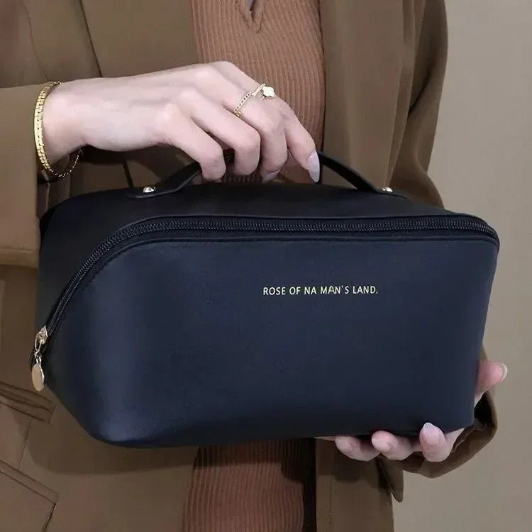 Une femme qui tient la trousse de toilette couleur noire afin d'en apprécier les caractéristiques