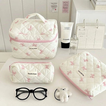Trousse de toilette 3 formats démontrés posée sur une table blanche 