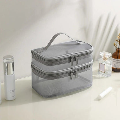 Trousse de toilette couleur grise posée sur un plan crème avec accessoires de maquillage à côté 