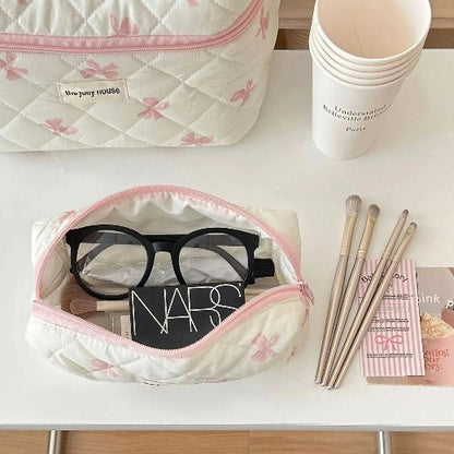Trousse de toilette grand format et format moyen posées sur une table blanche 