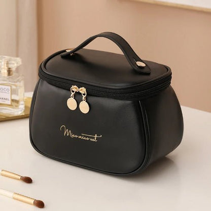 Trousse de toilette mini sac à main couleur noire posées sur un plan blanc avec accessoires de maquillage et de beauté autour