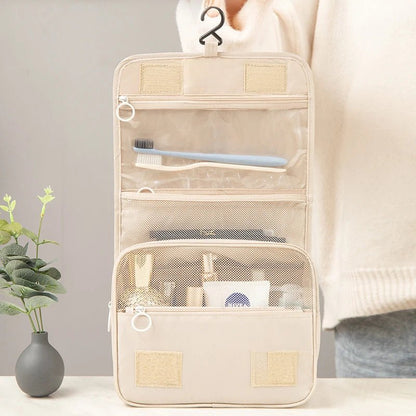 une femme qui tient ouverte la trousse de toilette nylon couleur beige afin d'en apprécier les caractéristiques