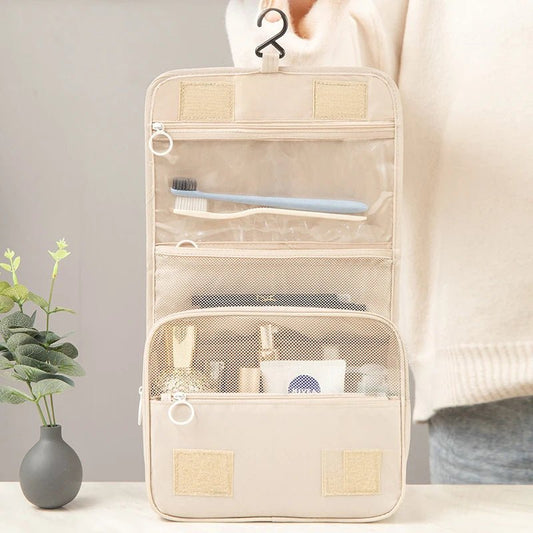 une femme qui tient ouverte la trousse de toilette nylon couleur beige afin d'en apprécier les caractéristiques
