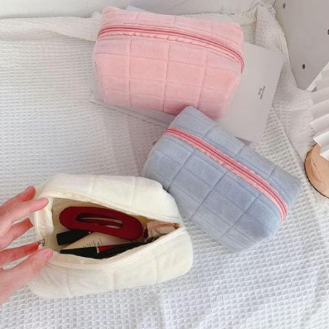 Trousse de toilette offerte en 3 couleurs posées sur une table décorative