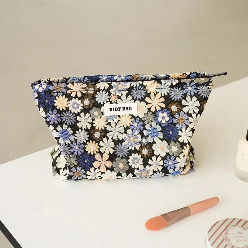Trousse de toilette fleurs bleues posée sur un plan blanc