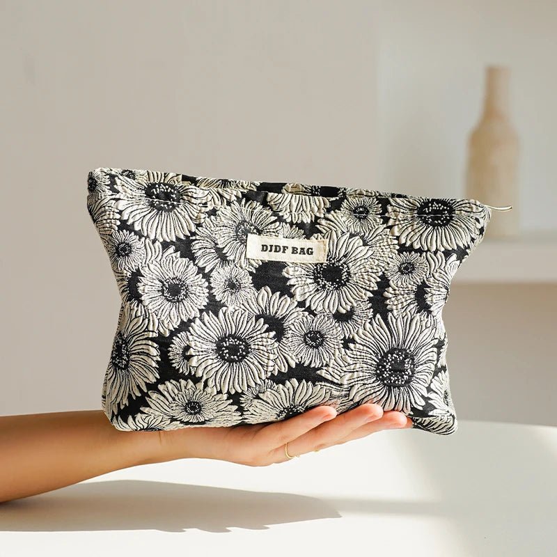 une femme qui tient dans sa main droite la trousse de toilette pochette couleur noire et blanche