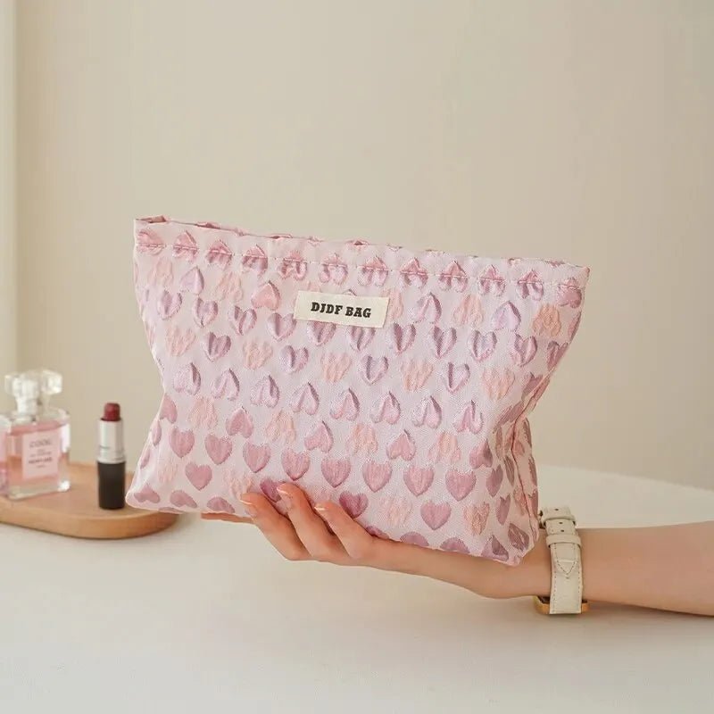 une femme qui tient dans sa main droite la trousse de toilette pochette couleur rose