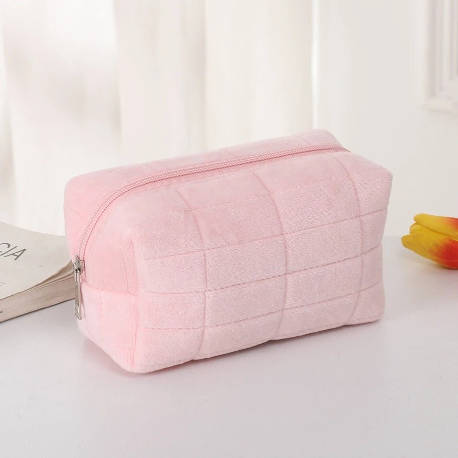 trousse de toilette offerte en couleur rose posées sur une table décorative blanche