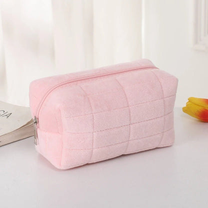 trousse de toilette offerte en couleur rose posées sur une table décorative blanche
