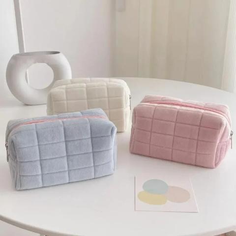 trousse de toilette offerte en 3 couleurs posées sur une table blanche décorative
