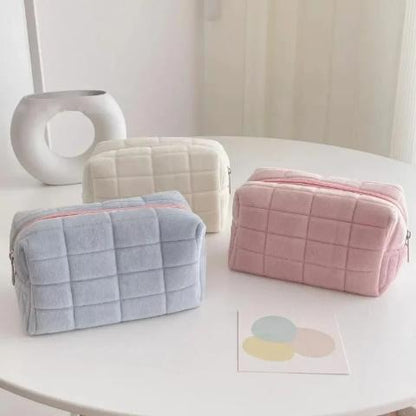 trousse de toilette offerte en 3 couleurs posées sur une table blanche décorative