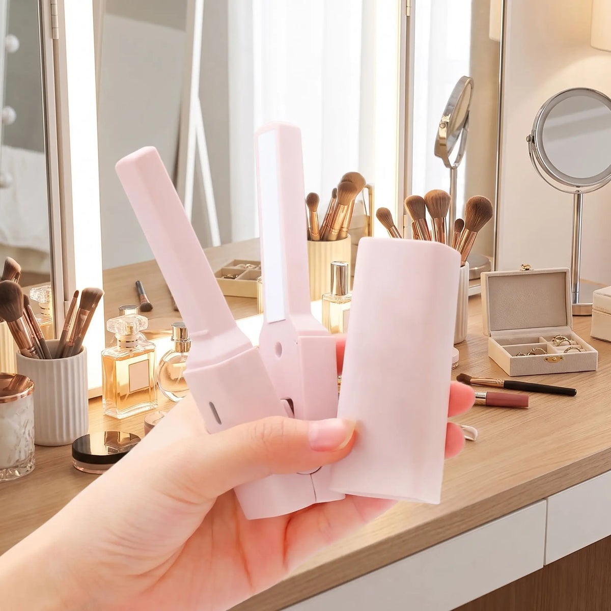 une main de femme qui tient le lisseur rose 